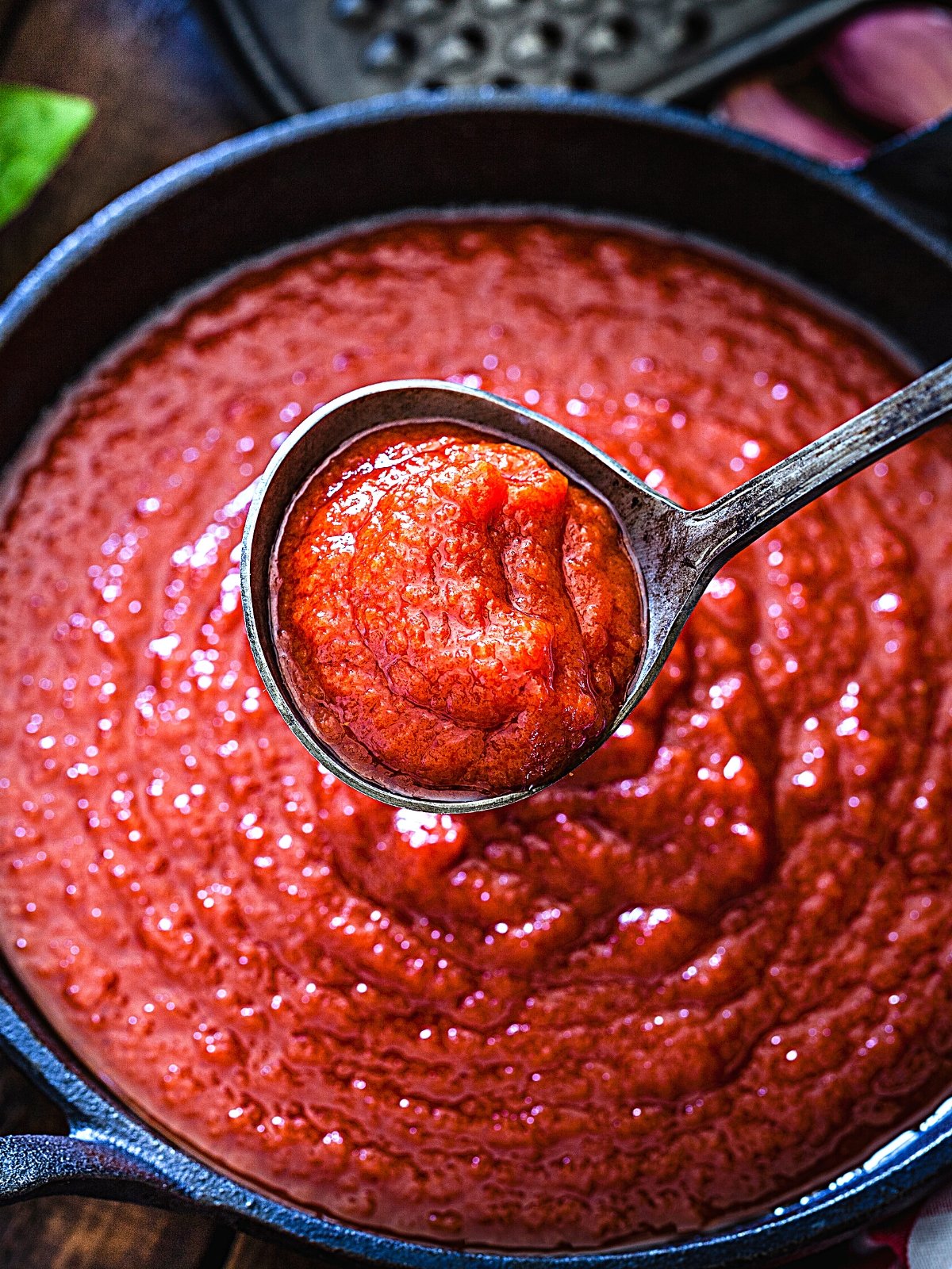 A ladle with Marinara Sauce lifting from a saucepan.