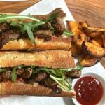 ribeye steak sandwich with arugula and onions.