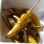 A bowl of homemade pickled serrano peppers with stems.