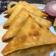 Fried chicken samosas displayed on a metal platter.