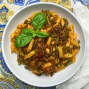 White bowl with green bean pasta with pancetta and basil.